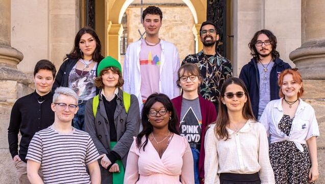 A group photo of some of the LGBTQ+ Soc committee members, on the steps of the Clarendon building